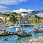 Riverside scene with boats, arch bridge, buildings, and blue sky