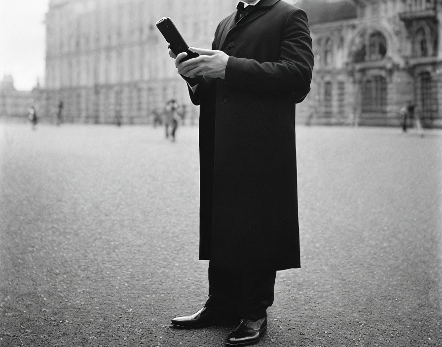 Person in suit holding smartphone with blurred building background