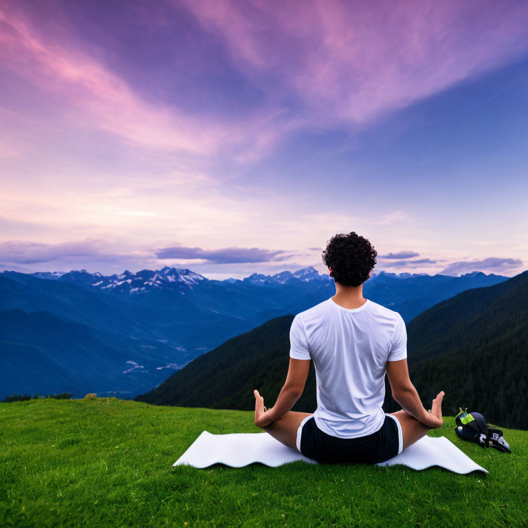 Meditating Person on Hill with Mountain View at Dusk