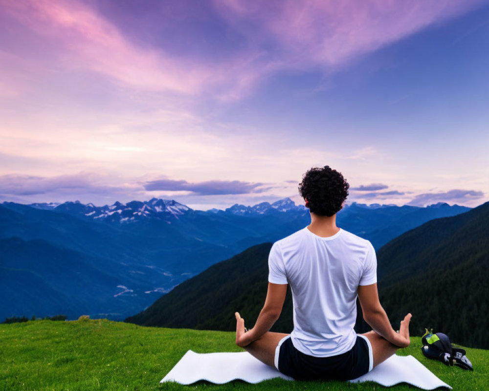 Meditating Person on Hill with Mountain View at Dusk