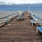 Wooden Dock with Fishing Rods Overlooking Calm Lake and Mountains