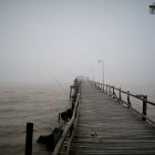 Wooden Pier in Foggy Landscape with Lightning Strikes and Glowing Orbs