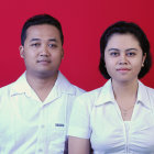 Asian man and woman in elegant white attire against red backdrop with floral elements