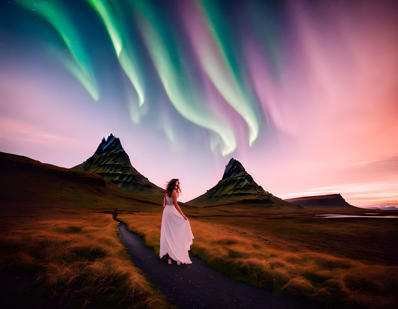 Woman in white dress on path amid aurora borealis-lit sky