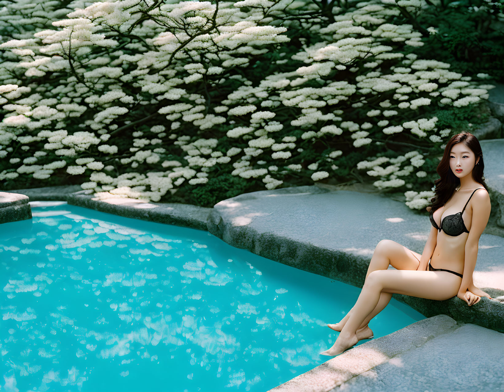 Woman in Black Swimsuit Relaxing by Tranquil Pool with Lush Plants