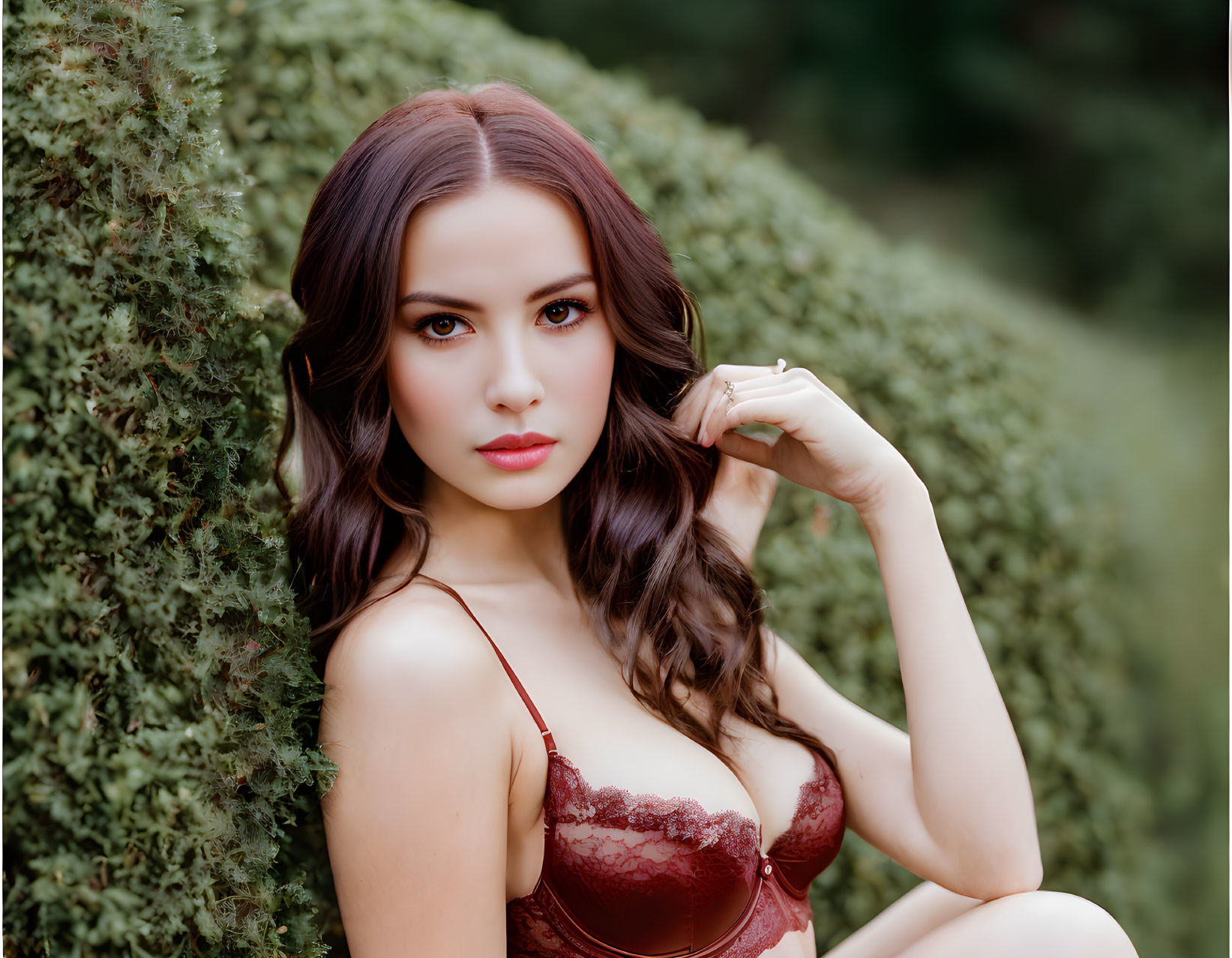 Long-haired woman in red lace dress against green background