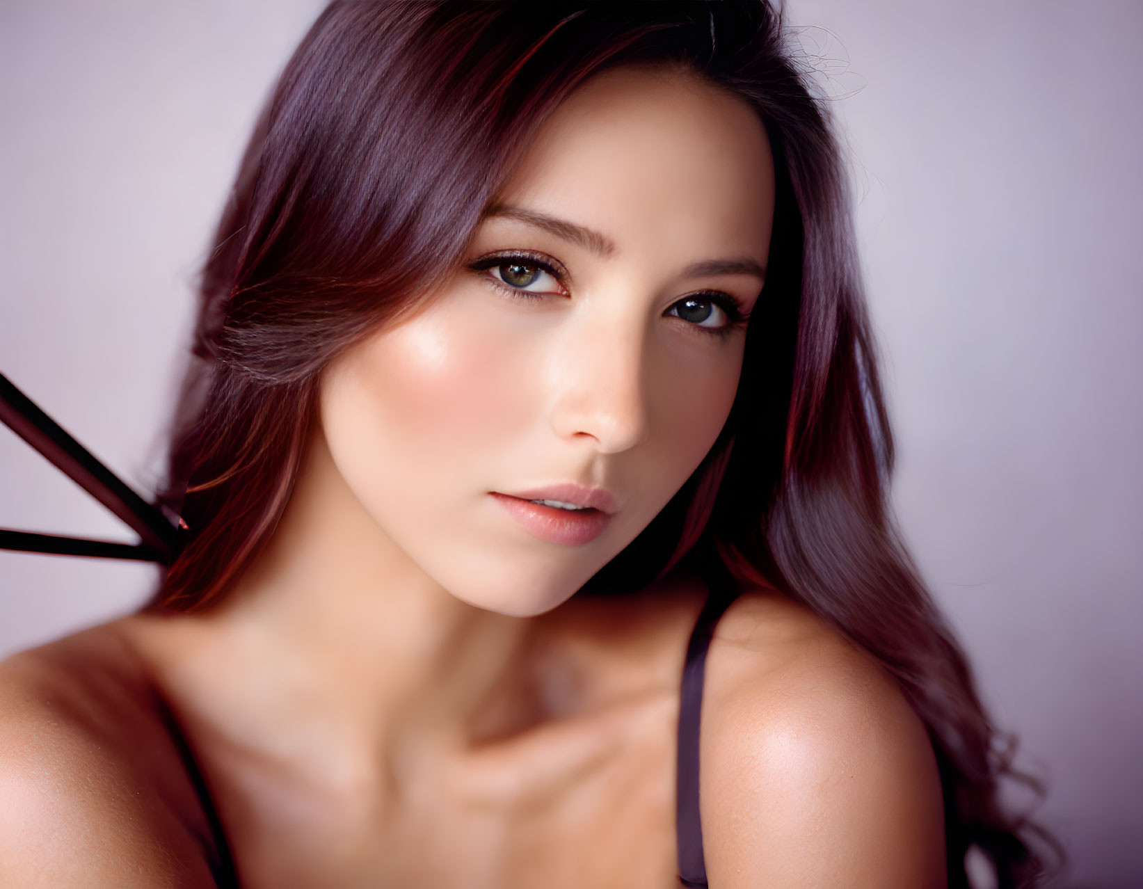 Dark-haired woman in close-up portrait against soft purple backdrop