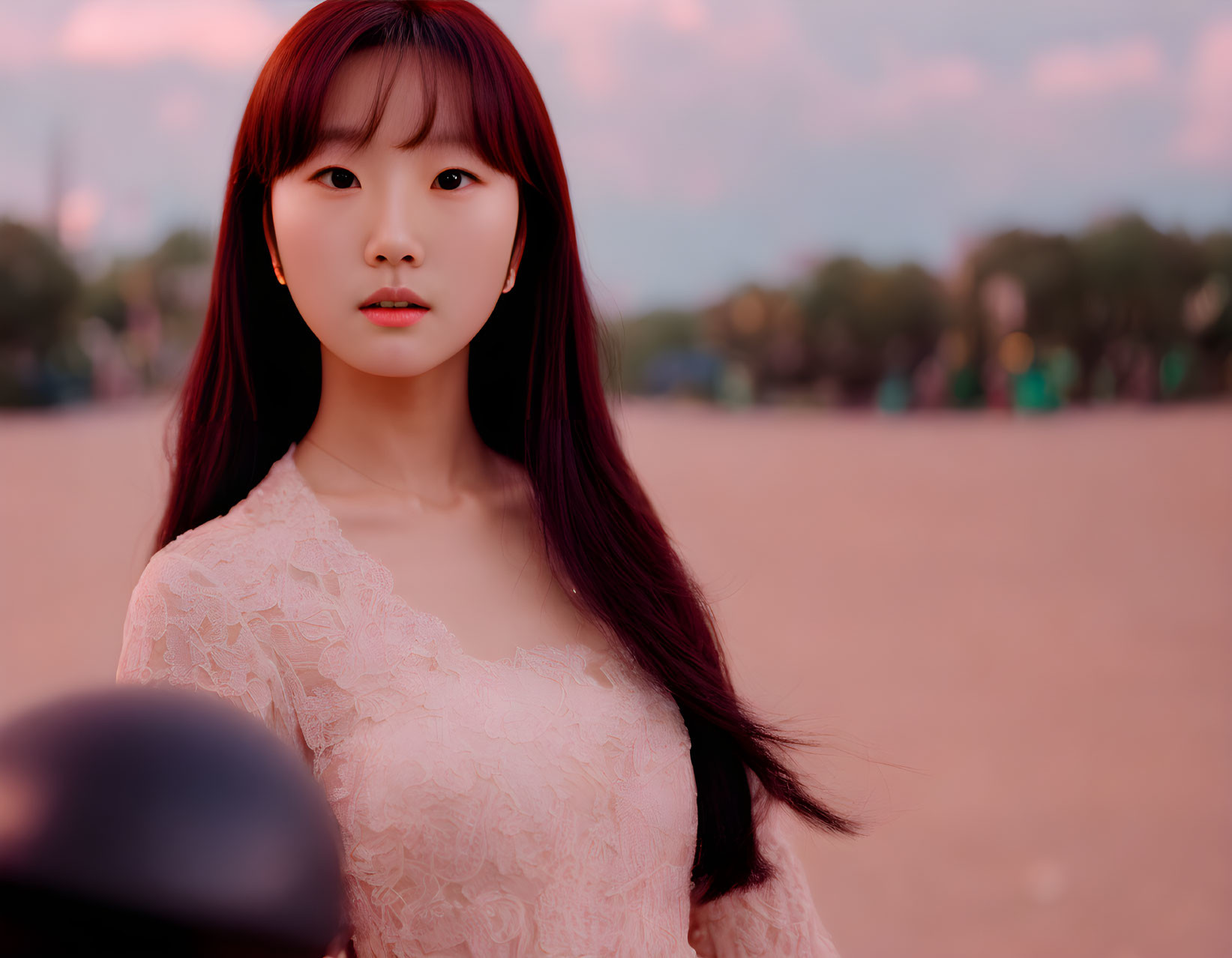 Young Woman in Lace Top Poses Against Sunset Sky