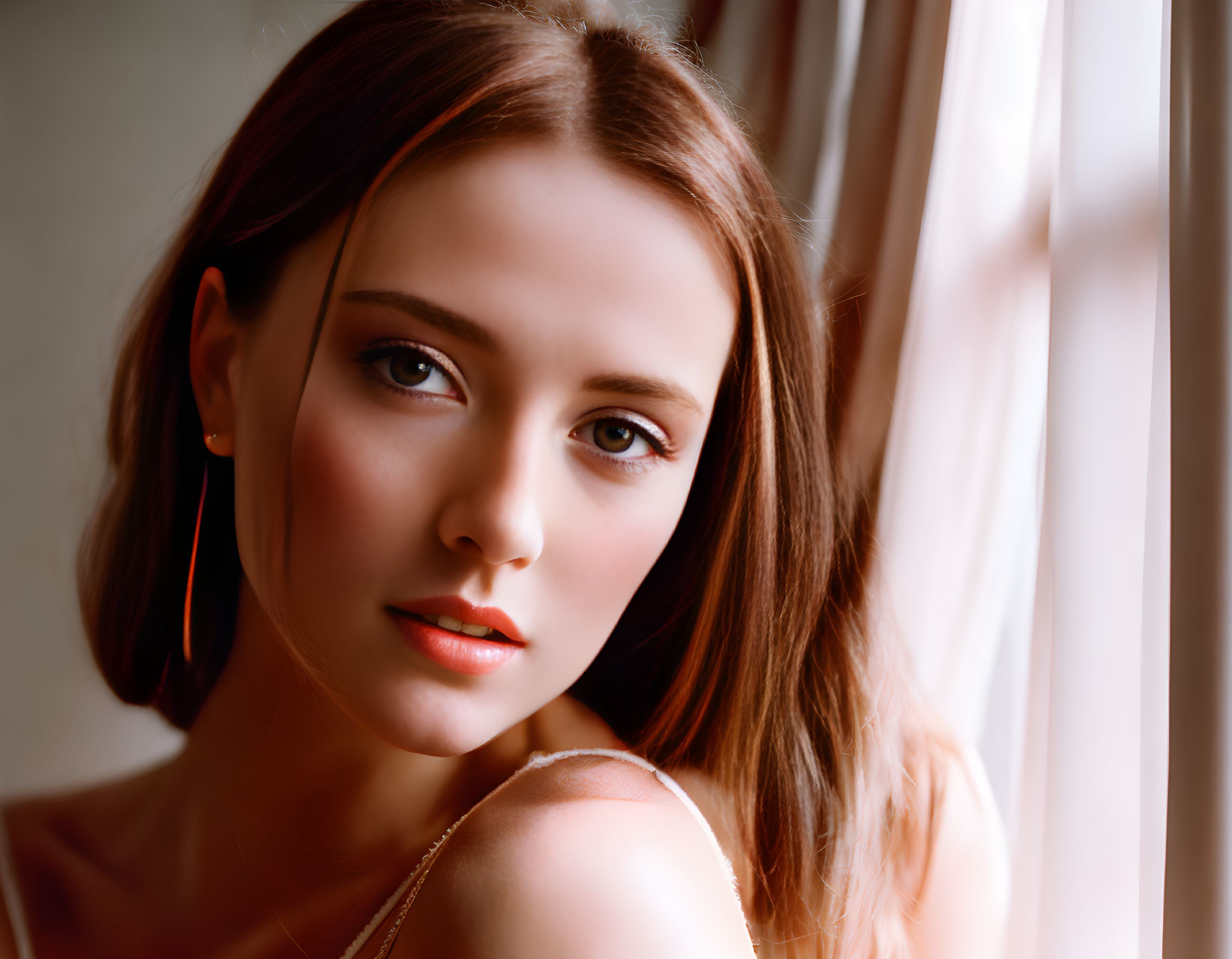 Contemplative woman with subtle makeup and earrings in soft natural light