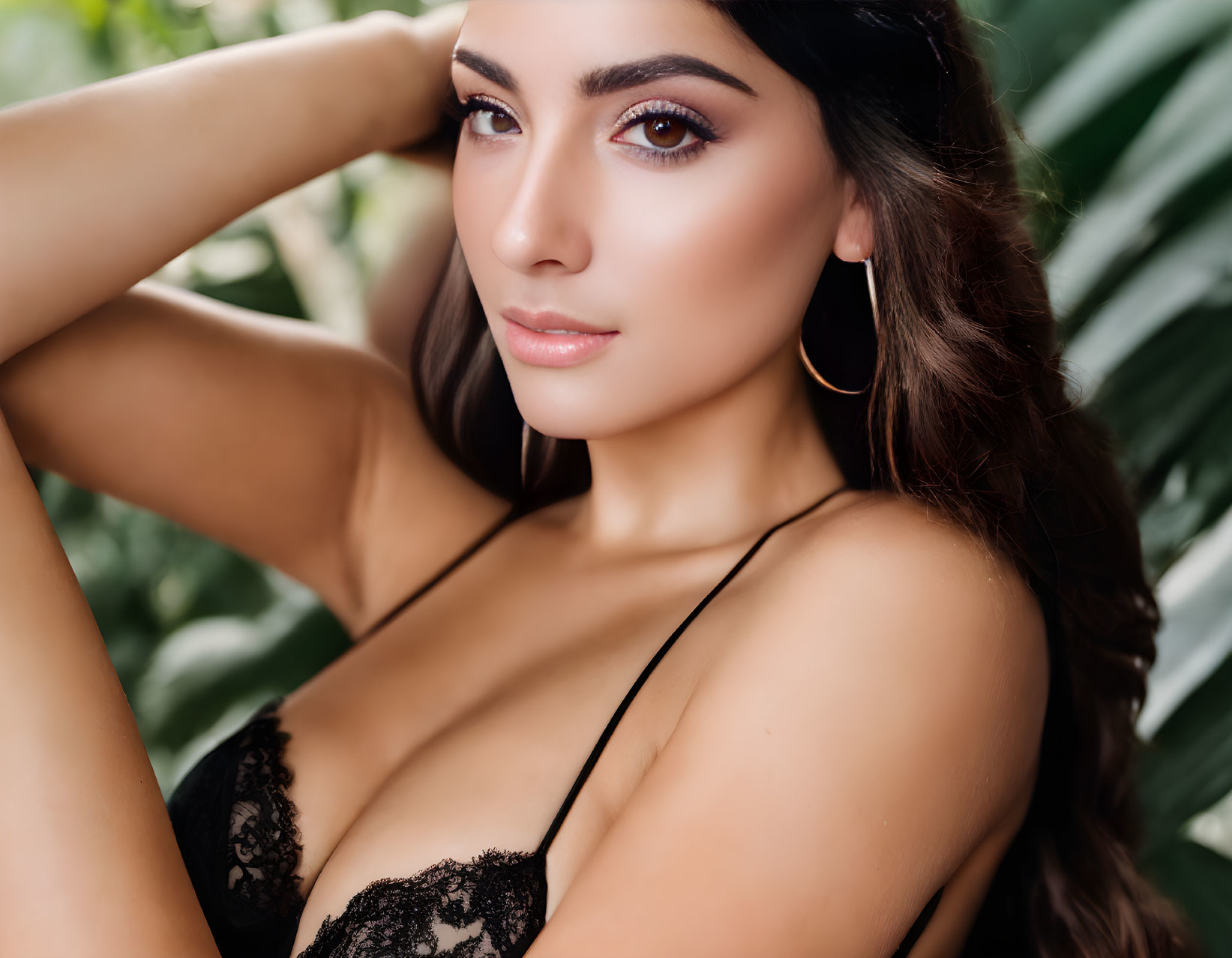 Dark-haired woman in lace attire poses against green backdrop.