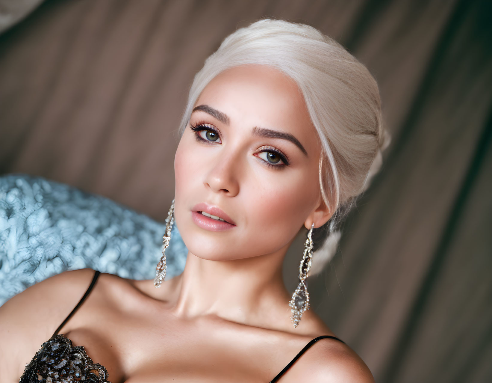 Platinum blonde woman in black top with shimmering earrings