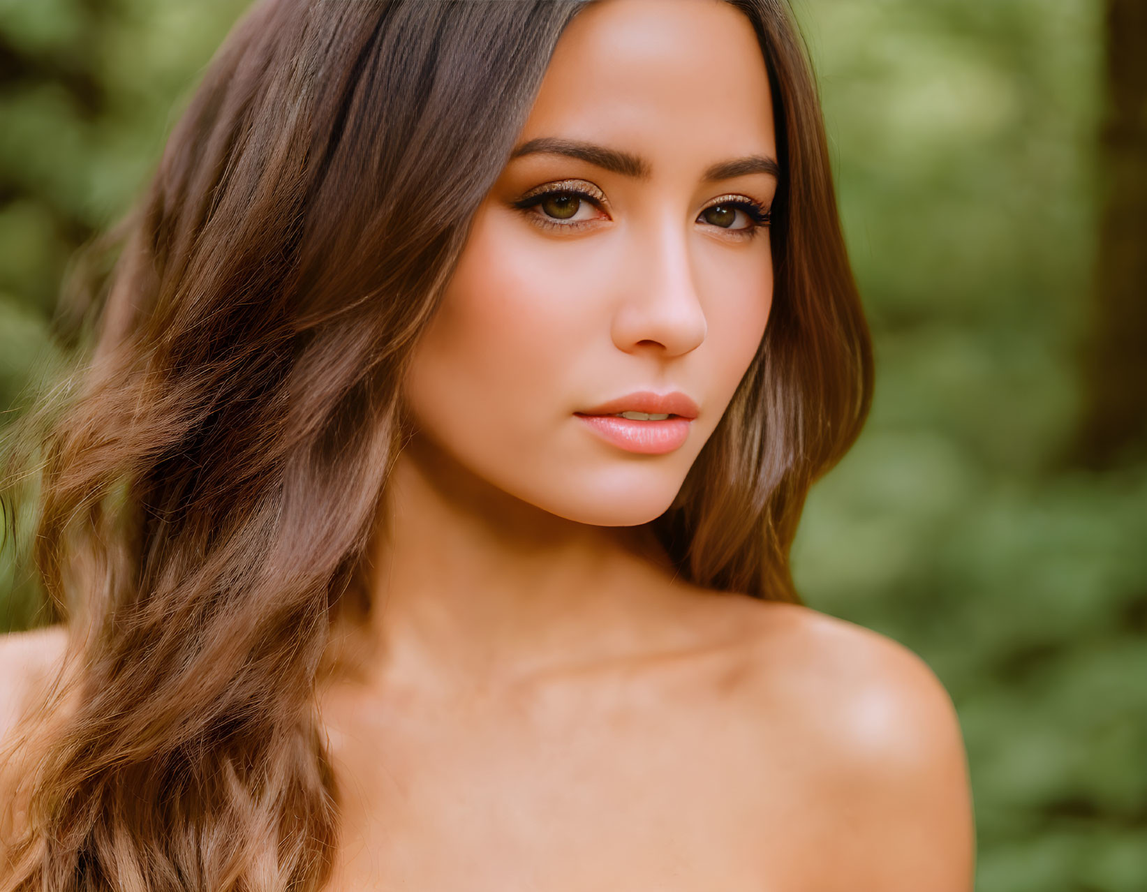 Brown-haired woman with subtle makeup gazing away in green natural backdrop