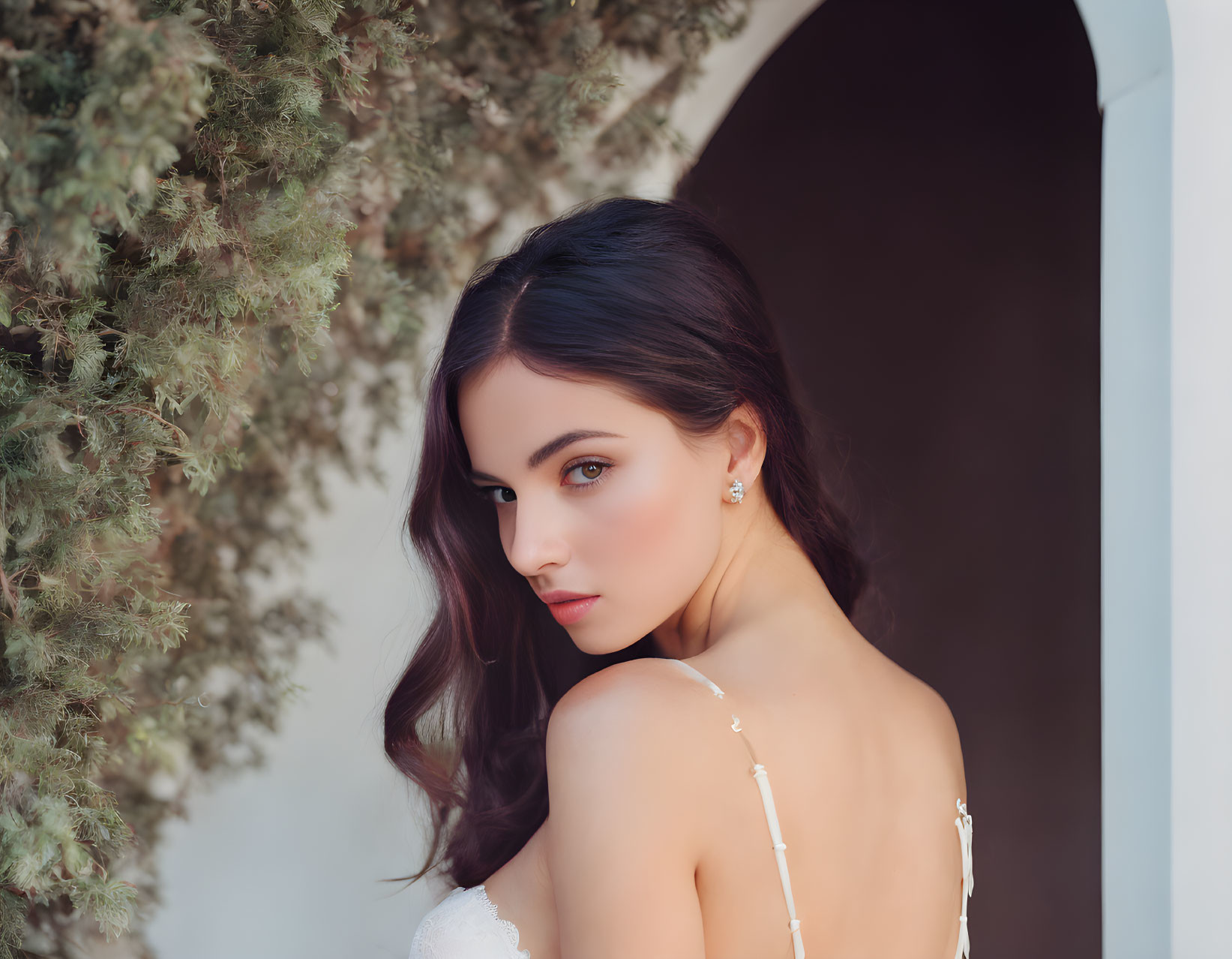 Dark-Haired Woman in White Dress with Archway Background