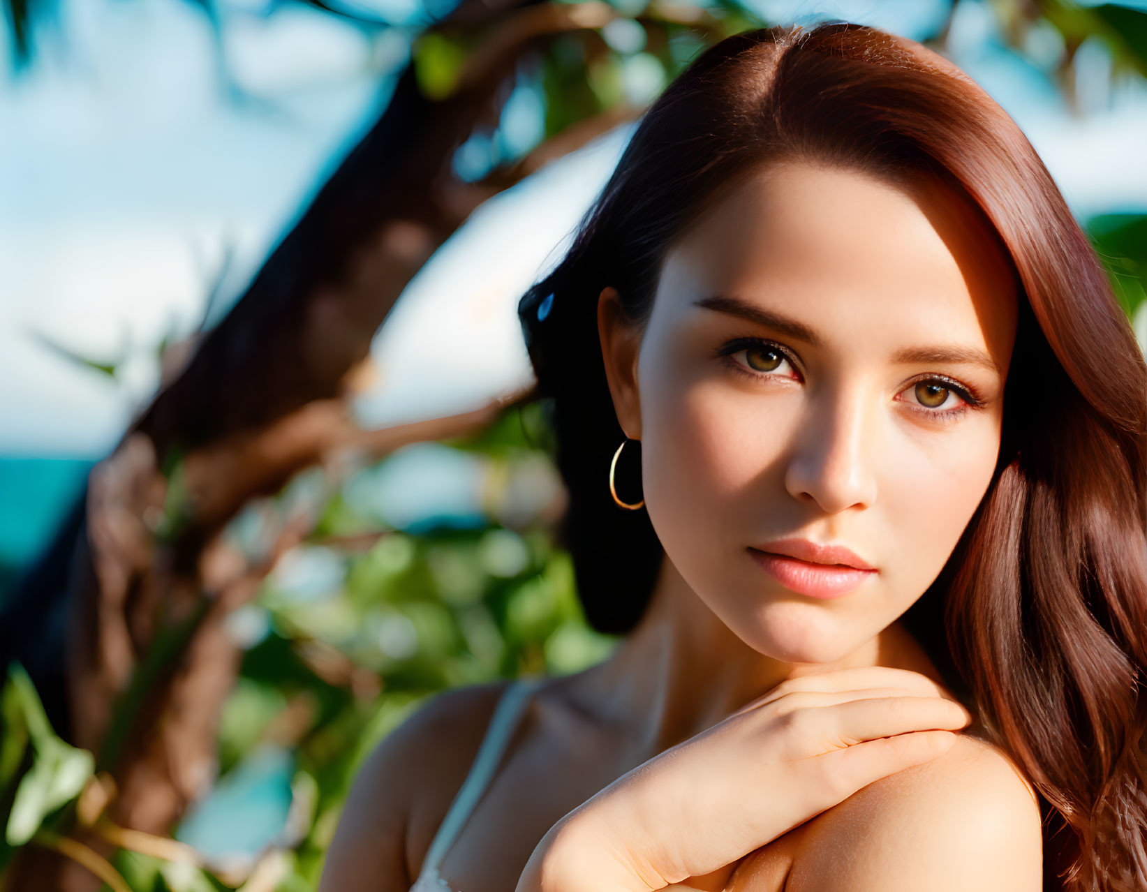 Brown-haired woman with subtle makeup gazing calmly against natural backdrop