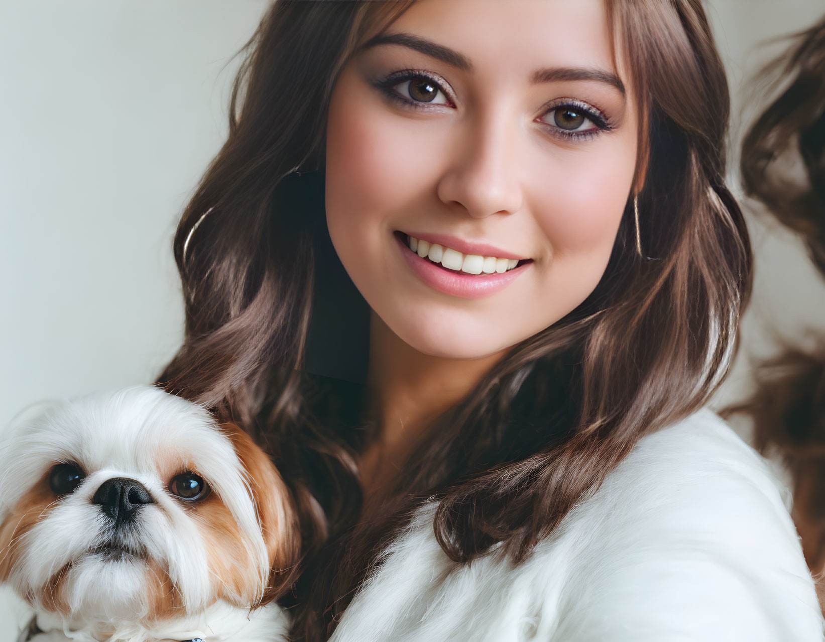 Smiling woman with brown hair holding fluffy white and tan dog