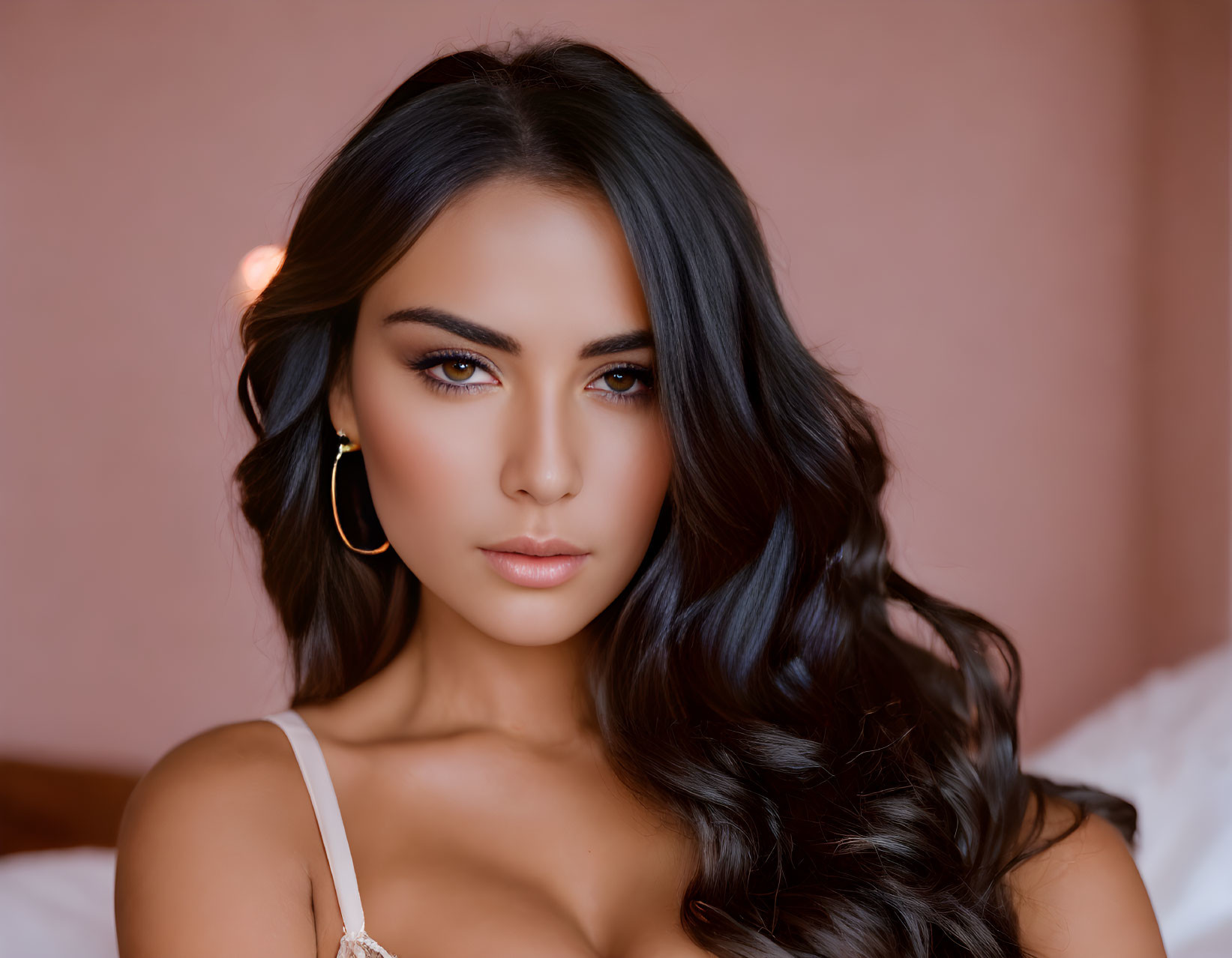 Long wavy hair, smokey eye makeup, hoop earrings woman in softly lit room