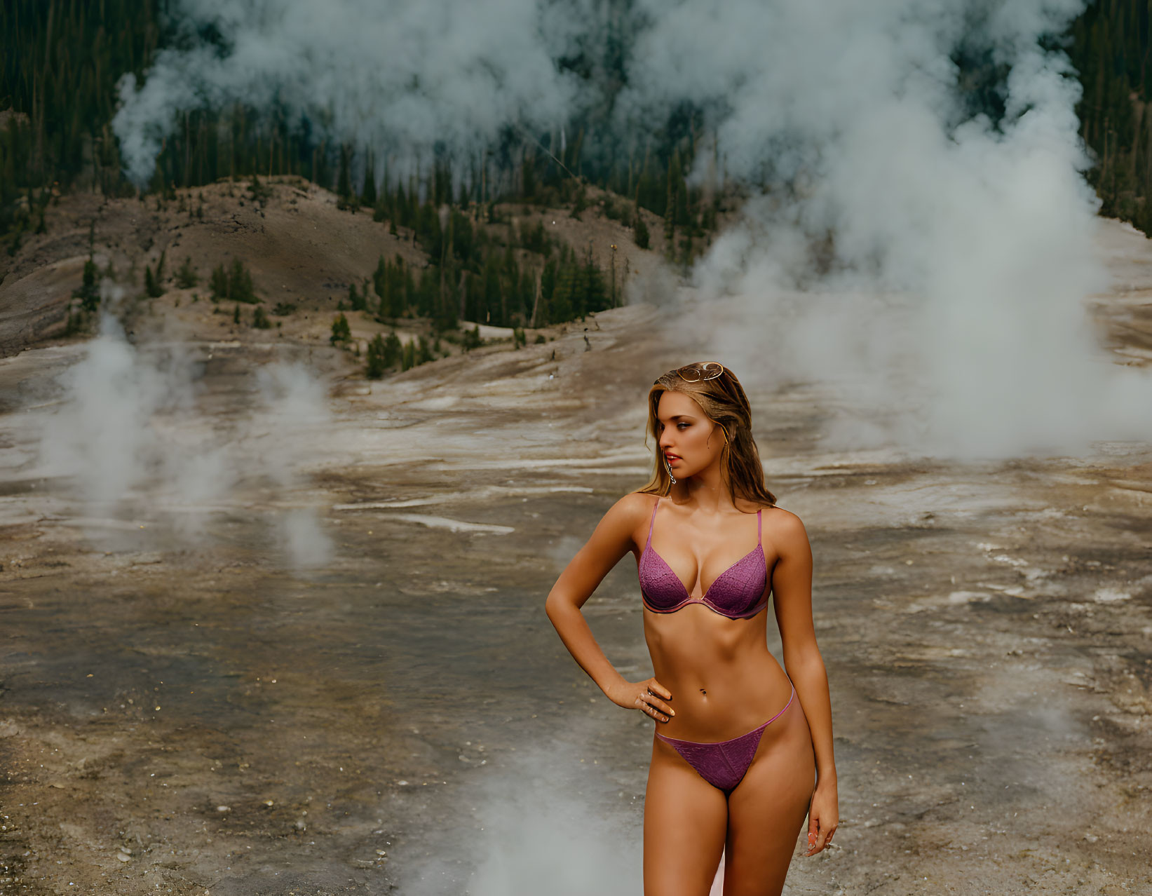 Woman in purple bikini with geothermal landscape and forested hills