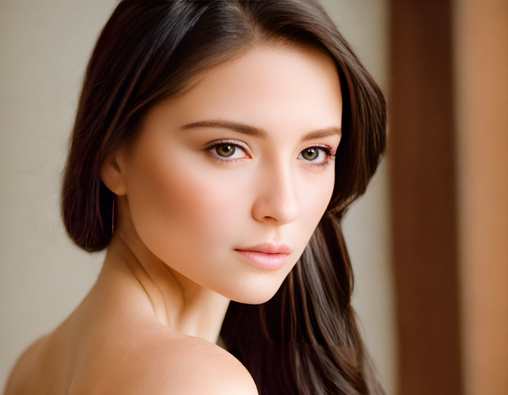 Portrait of woman with long dark hair and pink lips in soft-focus background