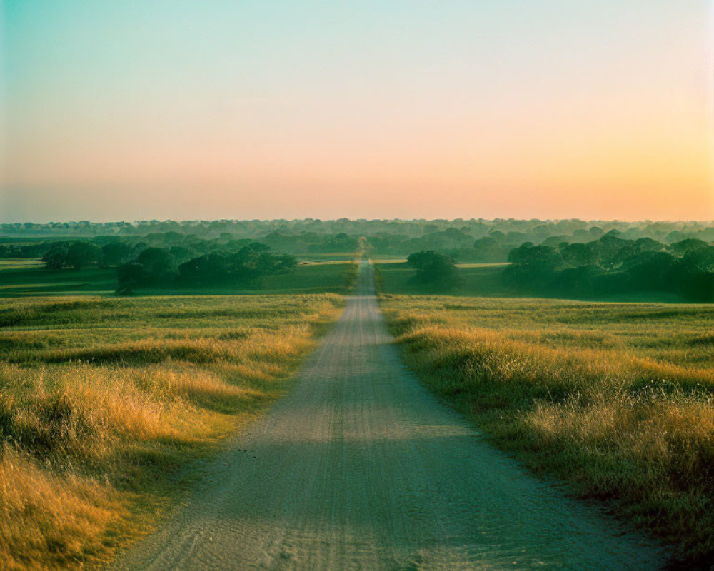 Tranquil rural road in vast fields under soft sunset sky