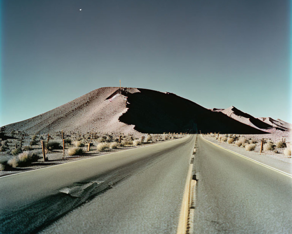 Straight road to hill under clear sky with crescent moon