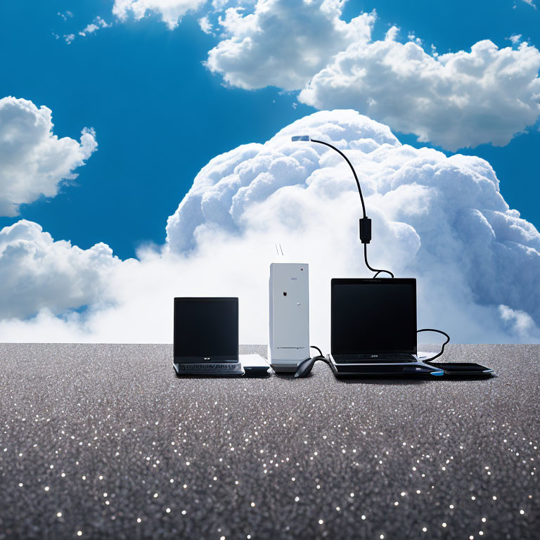 Two laptops connected by cables on glittery surface with router, against cloud-filled blue sky.