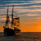 Two-masted sailboat at sunset over calm sea