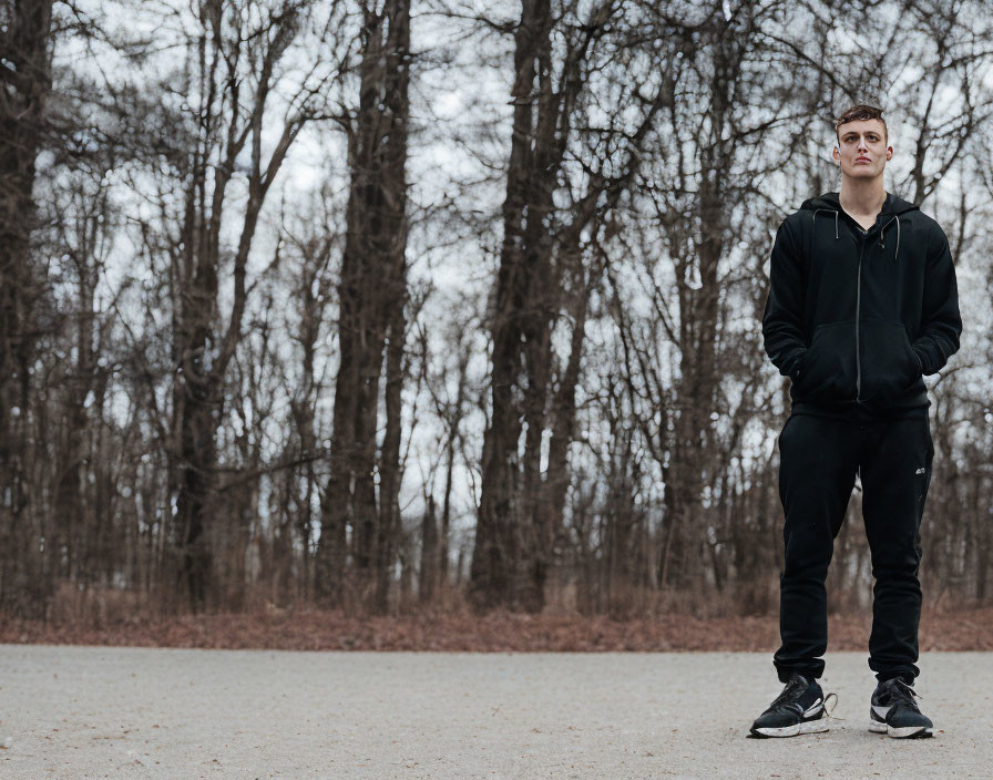 Confident Young Man in Black Sportswear on Barren Path