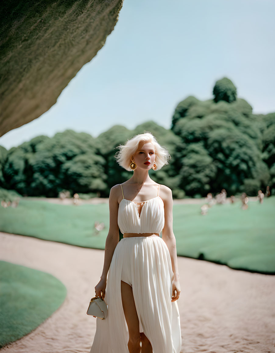 Woman in White Dress Strolling Gracefully in Sunlit Park