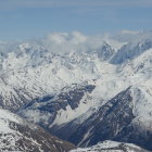 Snow-covered evergreen trees and sharp mountain peaks in panoramic winter landscape