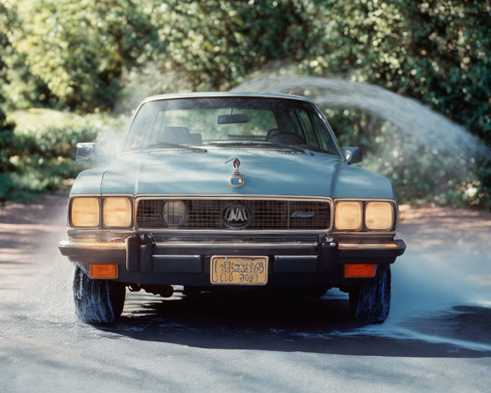 Vintage Blue Car Spraying Water on Wet Road Amid Greenery