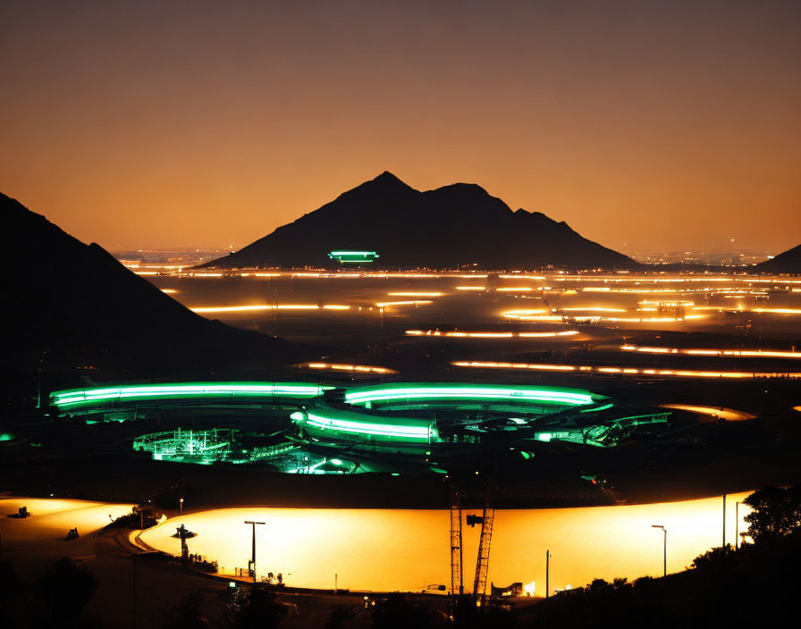 Brightly Lit Stadium at Night with Mountain Background