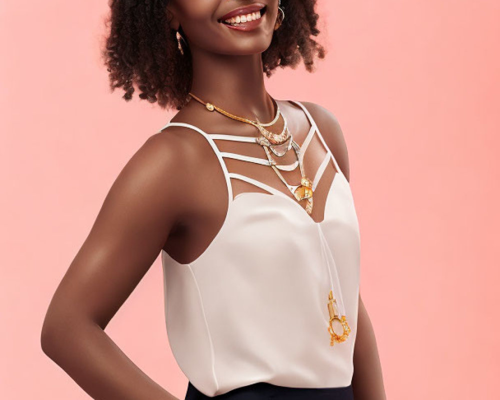 Smiling woman with curly hair in white top and navy bottom on pink background