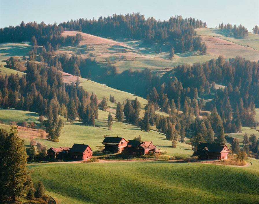 Landscape of rolling hills, green meadows, trees, and houses in soft light