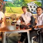 Three Men in Uniform Seated Around Wooden Table with Maritime Decor