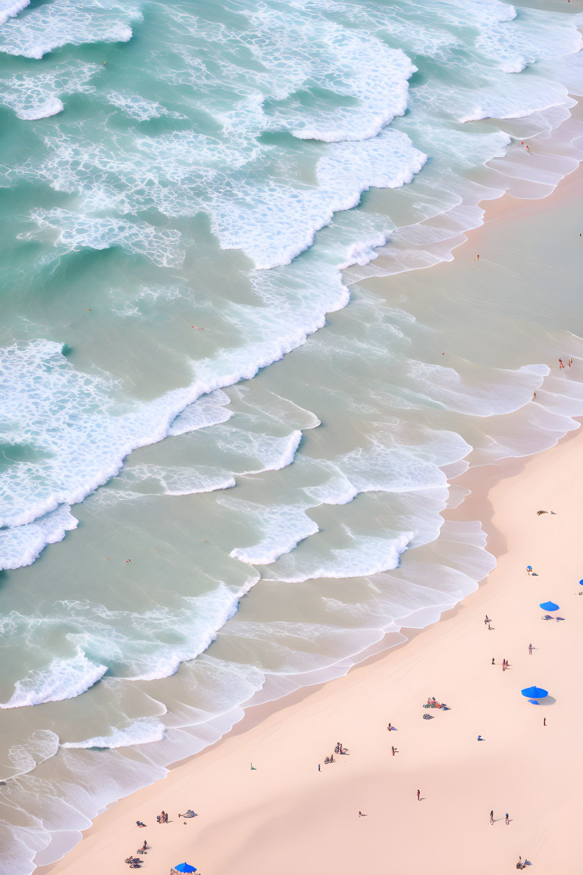 Sandy beach with rolling waves and people under blue umbrellas