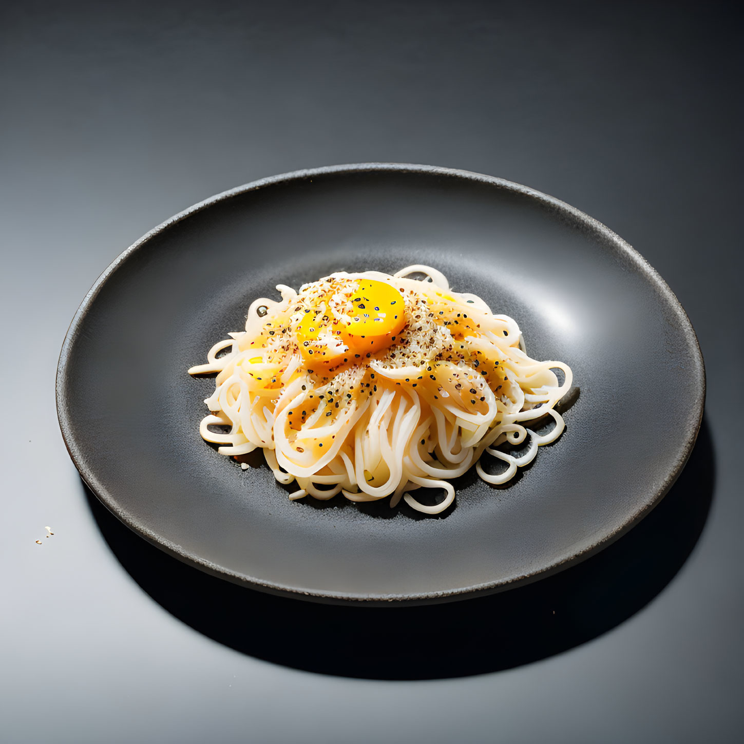 Spaghetti with Raw Egg Yolk and Black Pepper on Dark Dish