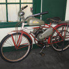 Vintage Motorcycle with Custom Golden-Brown Paint and Metal Details Beside Green Shuttered Window