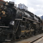 Steampunk-style train with gold detailing on industrial track and architecture