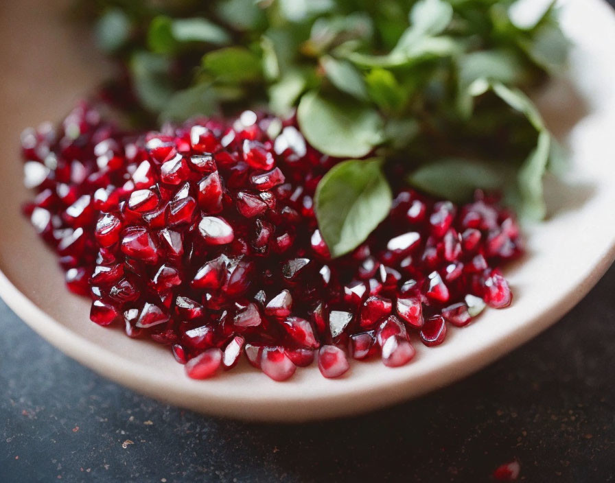 Fresh Pomegranate Seeds with Green Leaves on Dark Background