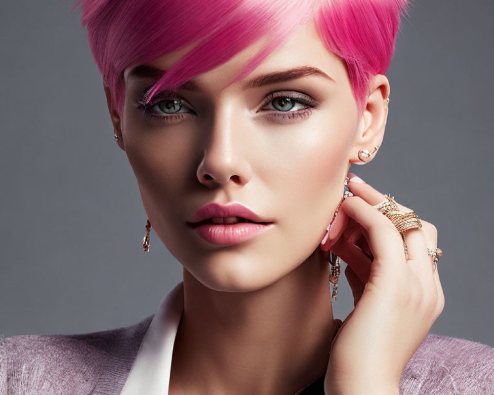 Portrait of woman with pink hair, blue eyes, and jewelry on grey background