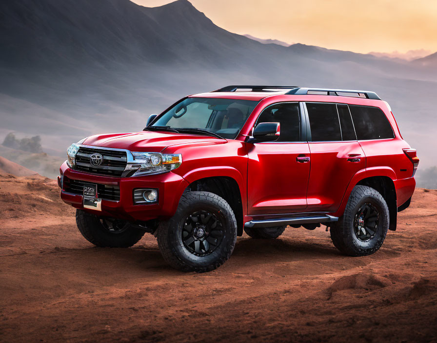 Red SUV on Dusty Trail with Misty Mountain Backdrop at Sunrise or Sunset