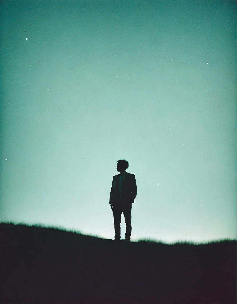 Silhouette of person on hilltop under starry night sky