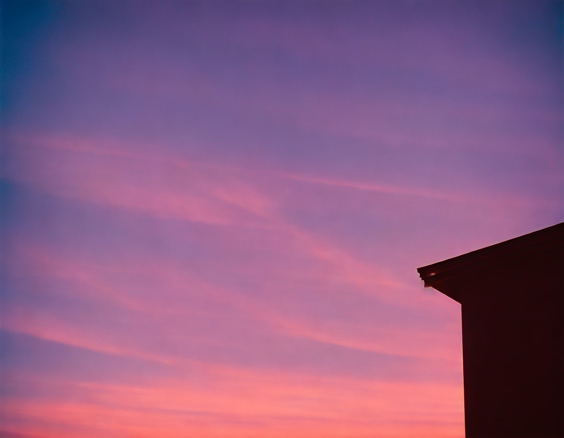 Twilight sky with pink and purple hues behind building silhouette