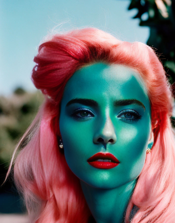 Vibrant pink hair and green face paint against blue sky