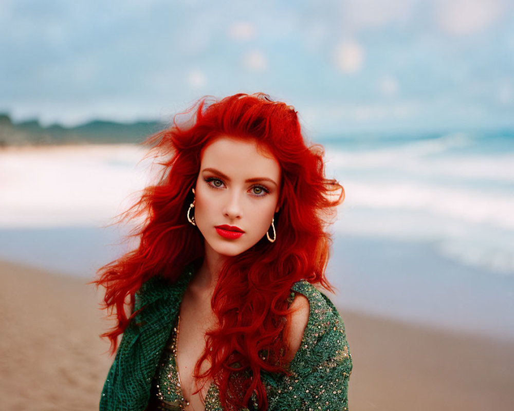 Vivid red-haired woman in green attire on beach with waves and cloudy sky