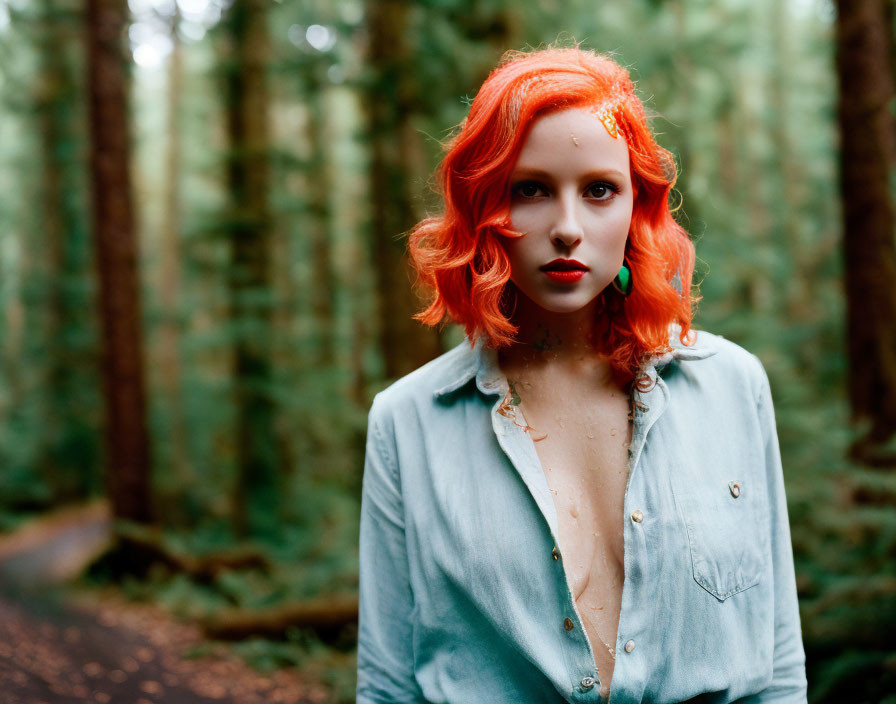 Woman with Bright Red Hair and Blue Shirt Standing in Forest