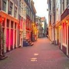 Amsterdam street at twilight with red-lit buildings, cobblestone road, parked bicycle