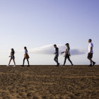 Family Walking on Beach Towards House on Pier with Children and Dog at Sunset