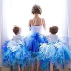 Three girls in blue tutu dresses and ballet shoes with floral hairpieces in a white setting