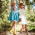 Two young girls in dreamy, flower-filled setting holding hands